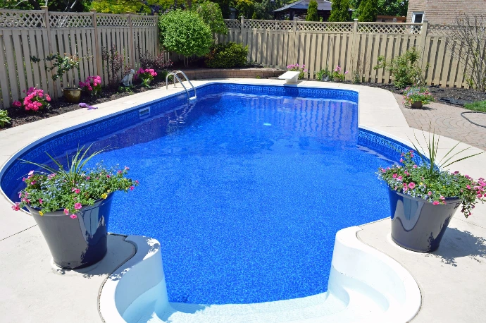 A dark blue pool liner showcased in backyard with flowers surrounding pool