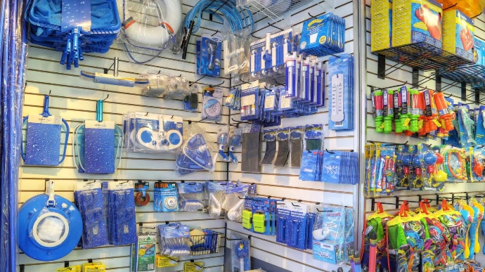 A store display featuring various pool accessories: nets, floats, and water toys, showcasing a vibrant assortment of blue and colorful items.